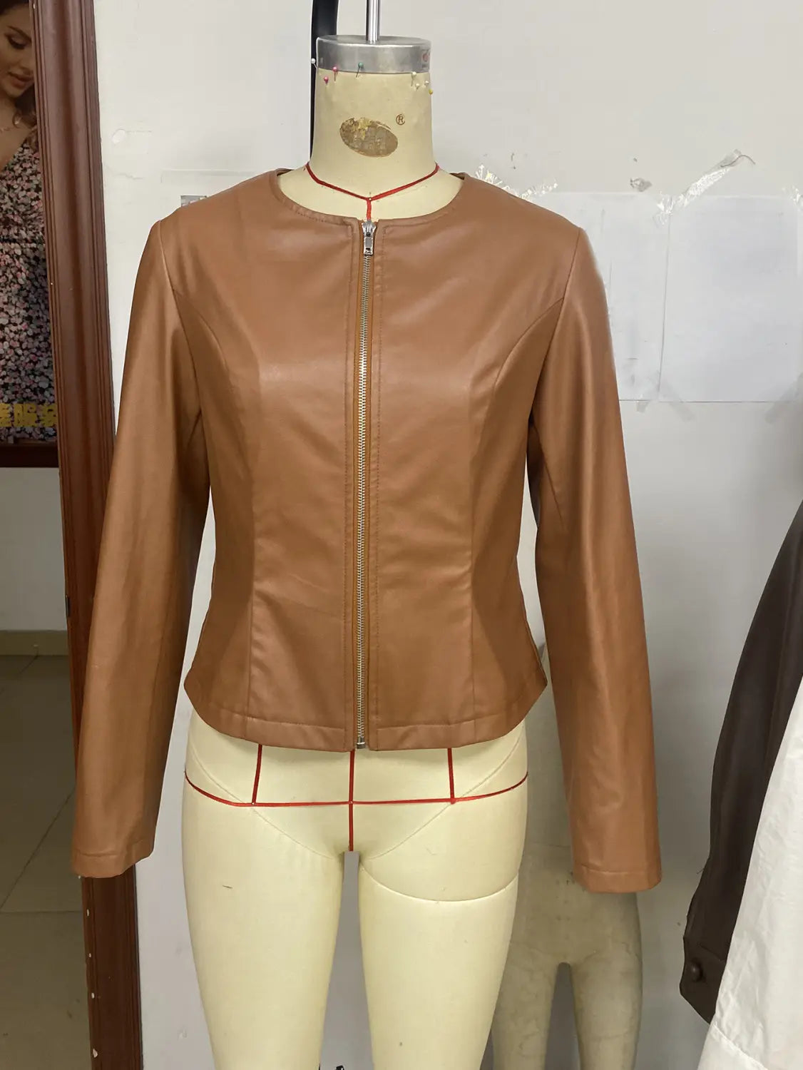Women’s tan faux leather bomber jacket with a sleek fitted design and subtle seam detailing featuring a zip-up front and long sleeves.