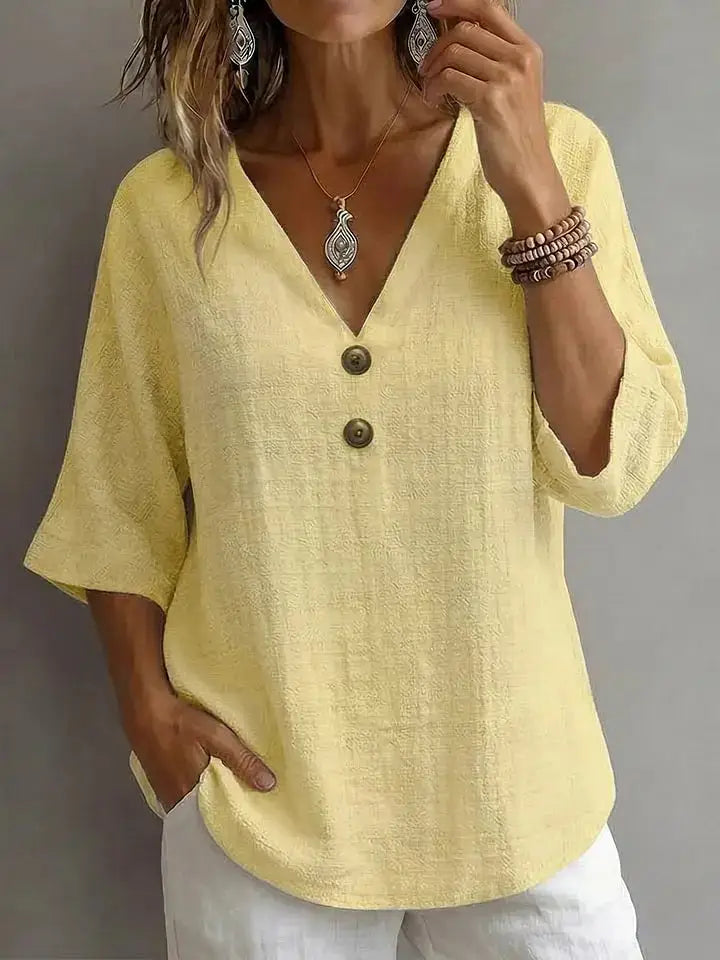 A soft pale yellow linen v-neck button top with three dark brown buttons down the front.