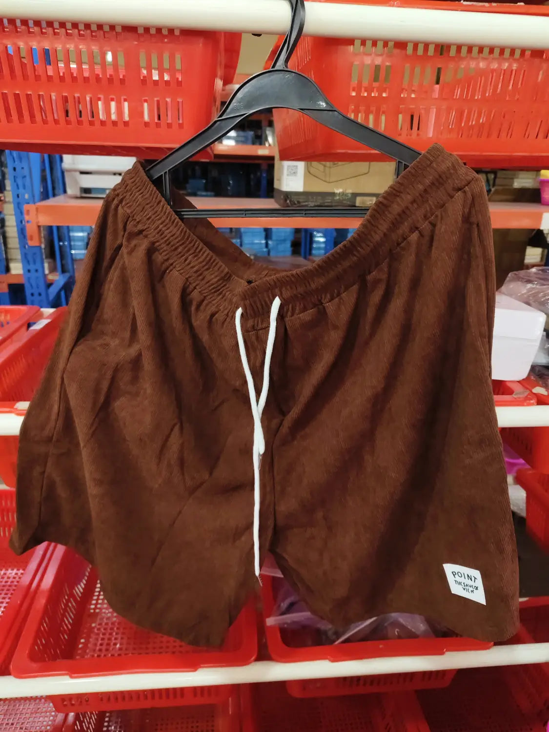 Shorts de sport en velours côtelé marron pour hommes avec des cordons de serrage blancs et une petite étiquette de marque « point » sur la partie inférieure droite de la jambe.