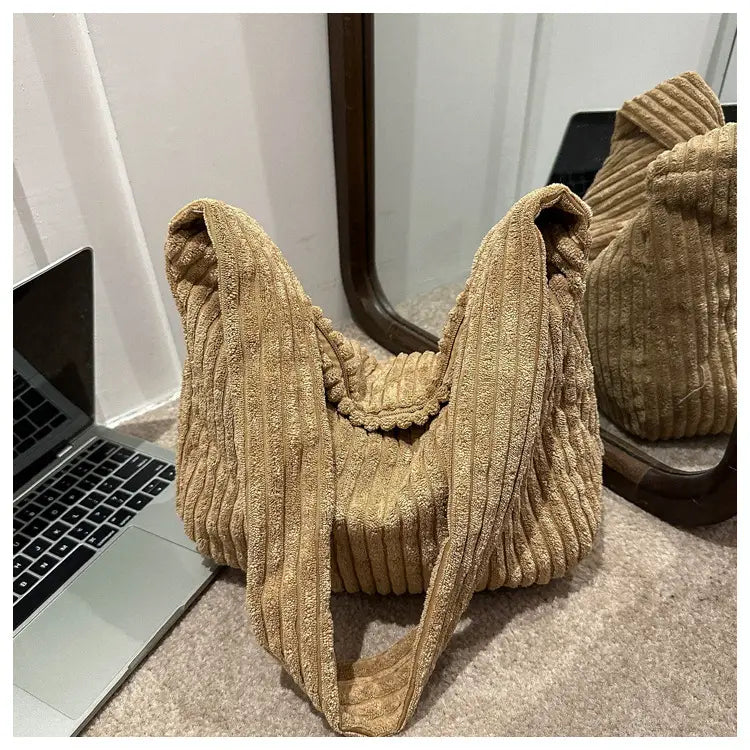 Beiger Corduroy-Schulterbeutel mit gerippter Textur und breiten, verstellbaren Schulterträgern, ausgelegt für minimalistisches Streetwear.