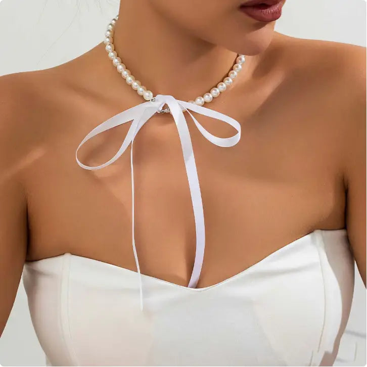 A delicate white pearl choker necklace adorned with a soft black satin ribbon bow in a black satin and pearl ribbon choker bow jewelry set.