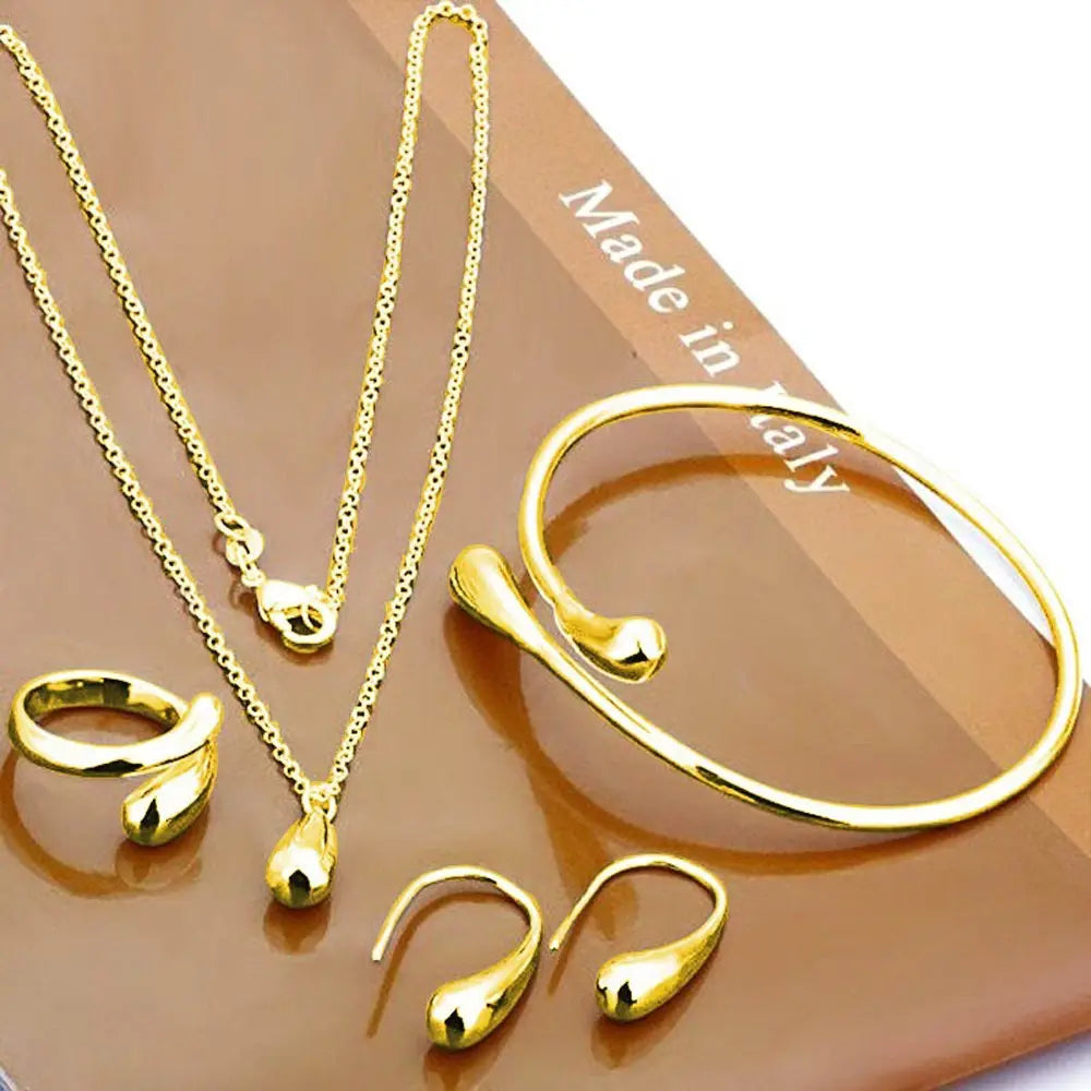 Modernes silbernes tropfenförmiges schmuckset mit einer goldfarbenen kette, einem armband, einem ring und ohrringen mit eleganten metallischen oberflächen.