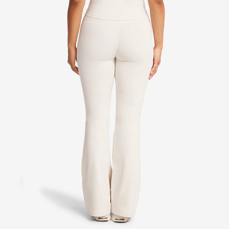 Leggings de yoga couleur crème taille haute évasée fabriqués dans un tissu lisse et extensible pour un port confortable.