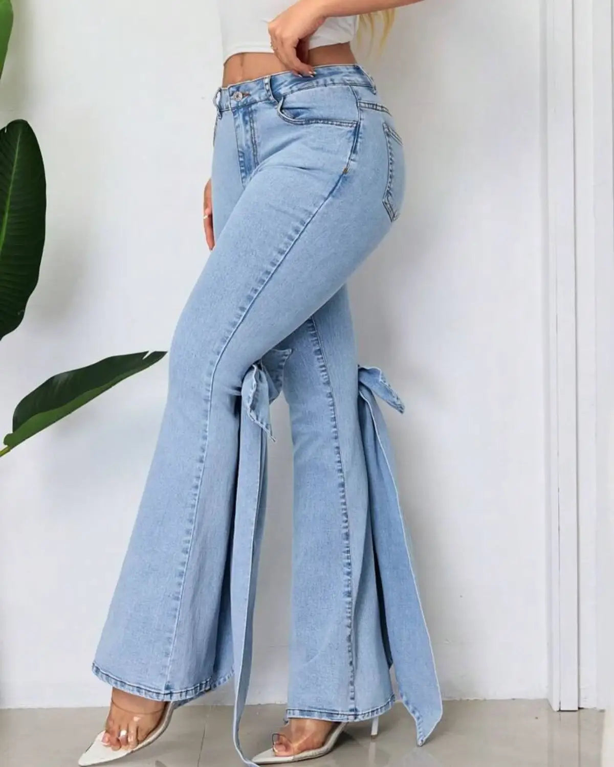 Jean taille haute à coupe évasée en denim bleu clair avec effet délavé clair et détail sur le côté noué.