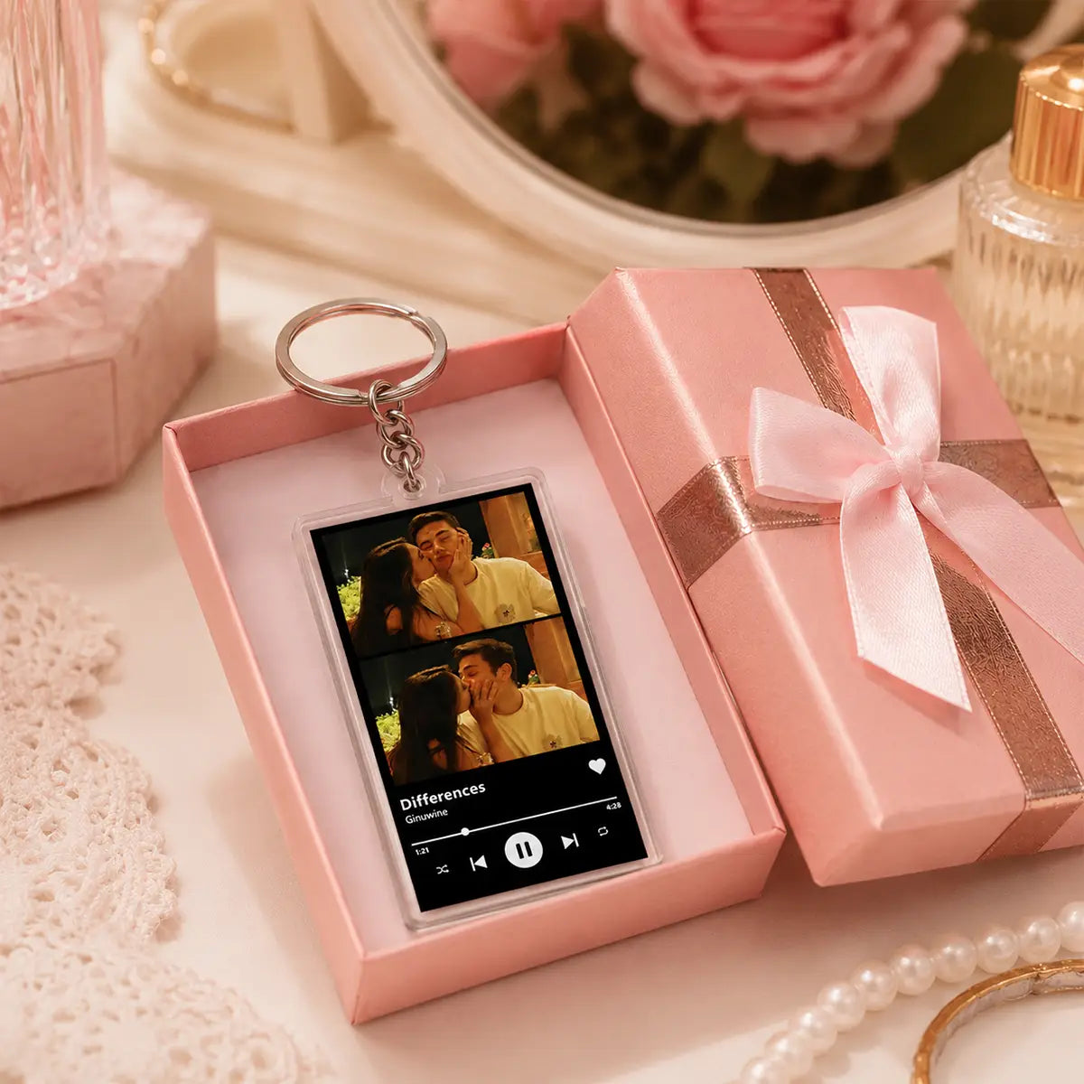 A rectangular transparent acrylic custom Spotify music player keychain features a printed photo of two people kissing and displays the song differences by Ginniwe on its screen attached to a silver metal ring.