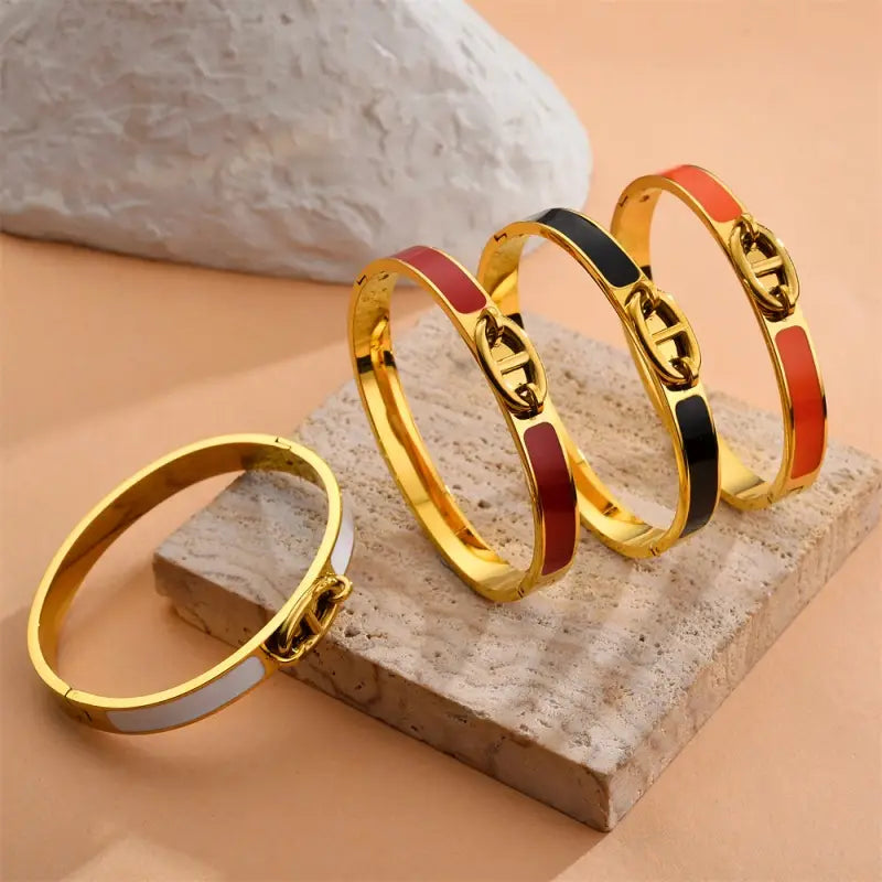 Women h bangle gold enamel minimalist bracelet featuring gold-tone bangles with enamel inlays and a signature logo clasp available in red black and white as a bangle fashion bracelet.