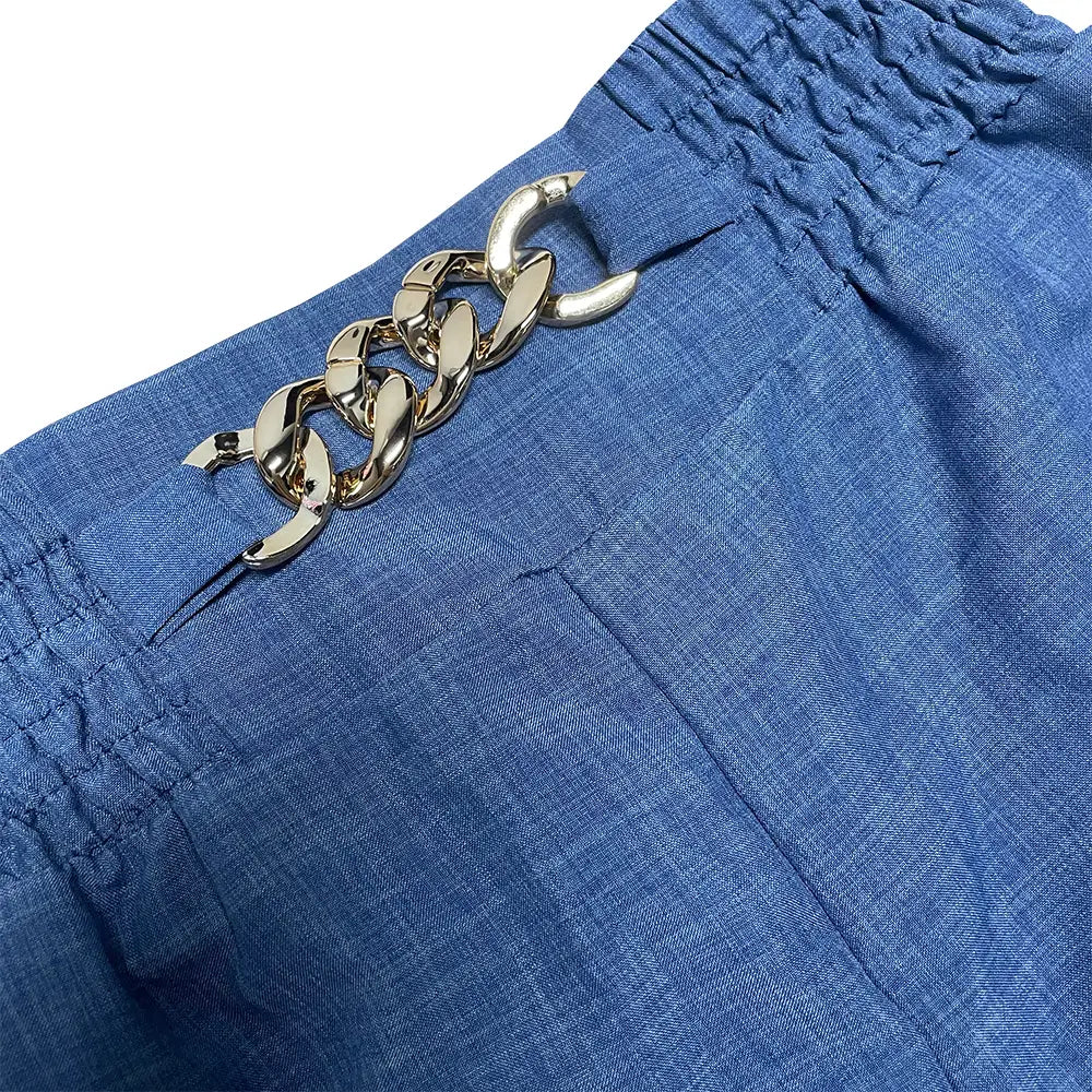 Short en denim bleu à jambes larges avec une boucle de ceinture à chaîne très visible aux tons dorés, adapté à une tenue décontractée et au bureau