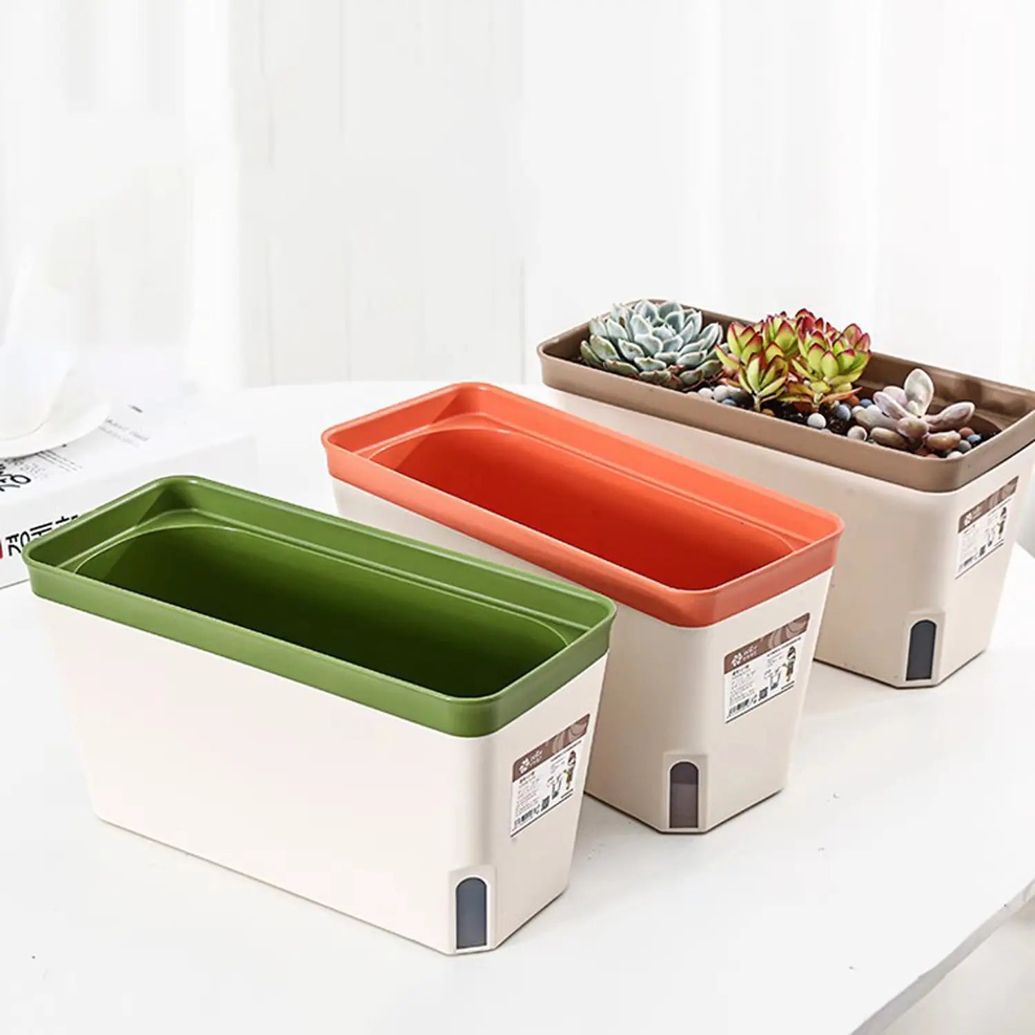 Rechteckige Kunststoff-Blumentöpfe in Grün, Orange und Beige mit passenden Rändern, mit automatischem Bewässerungssystem zur Selbstbewässerung mit Baumwollstreifen für eine effiziente Pflanzenpflege.