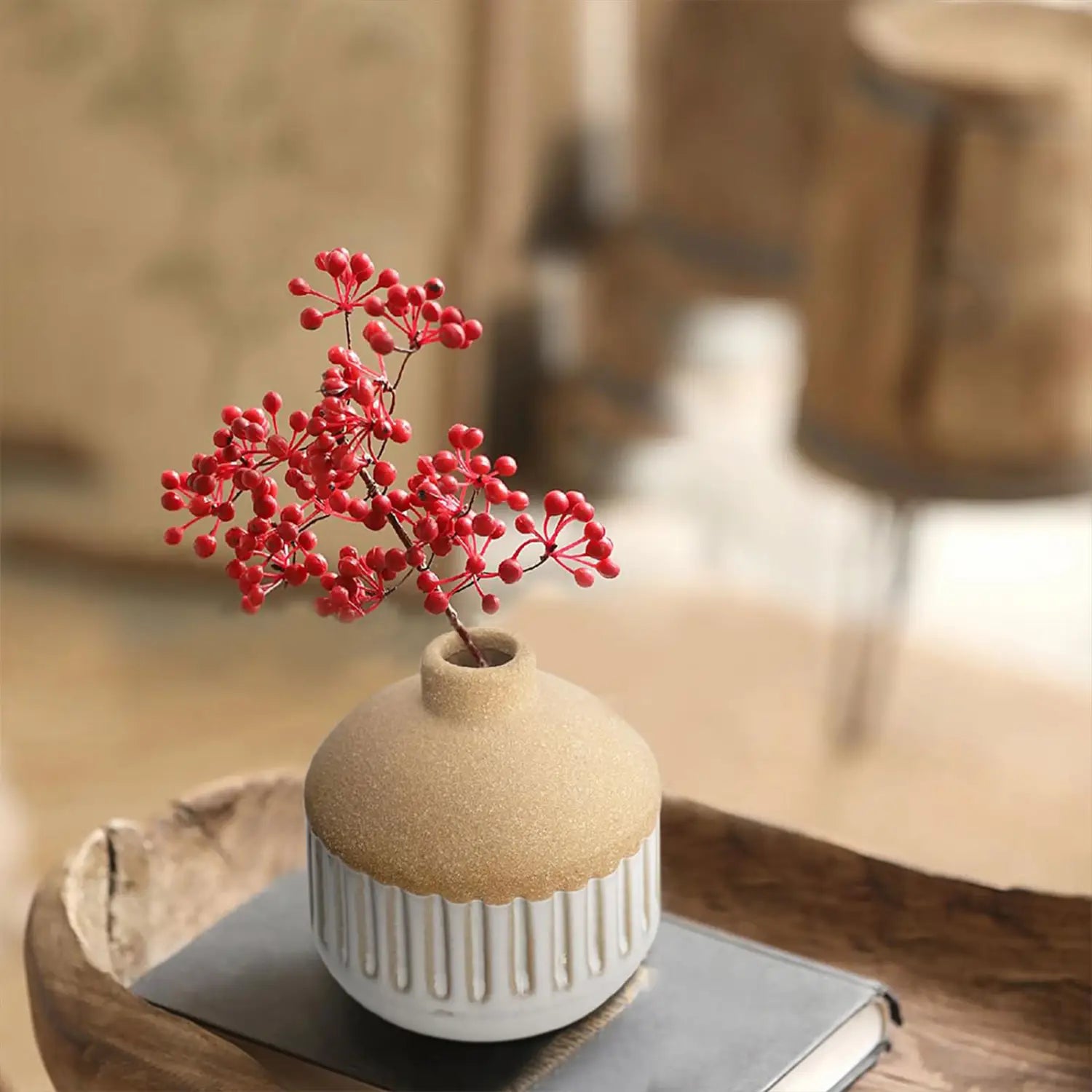 a beige ceramic flower vase with vertical ridges and a textured earthy finish holding vibrant red berry branches as boho tabletop decor