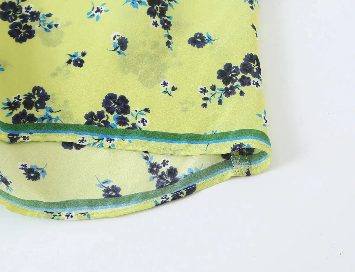 Ein leuchtend gelbgrünes Seidentuch mit zartem dunkelblauem und hellblauem Blumenmuster sowie dünnem grünem Rand, passend zu einem floralen zweiteiligen Midi-Rock-Set im Boho-Outfit-Stil.