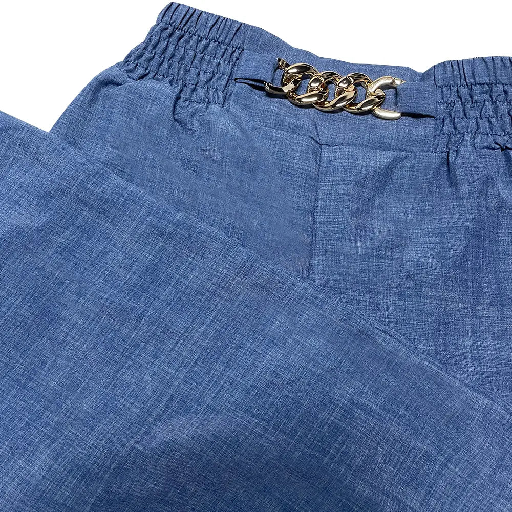 Pantalon en denim bleu à jambes larges pour femmes avec une boucle de ceinture à chaîne aux tons dorés au niveau de la taille, adapté à des pantalons habillés décontractés au bureau