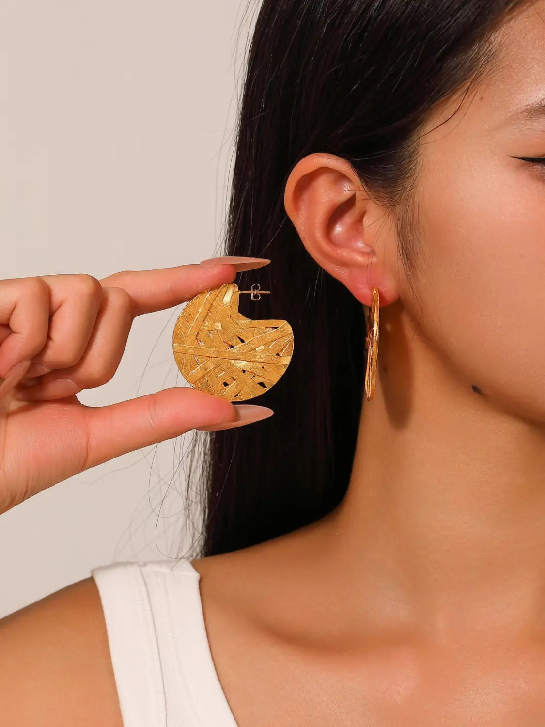 Ohrringe mit abstraktem Tropfen-Design, vergoldet mit 24k Gold, mit einem goldfarbenen kreisförmigen Hoops-Design mit einem strukturierten geometrischen Muster und einem offenen Rückendesign.