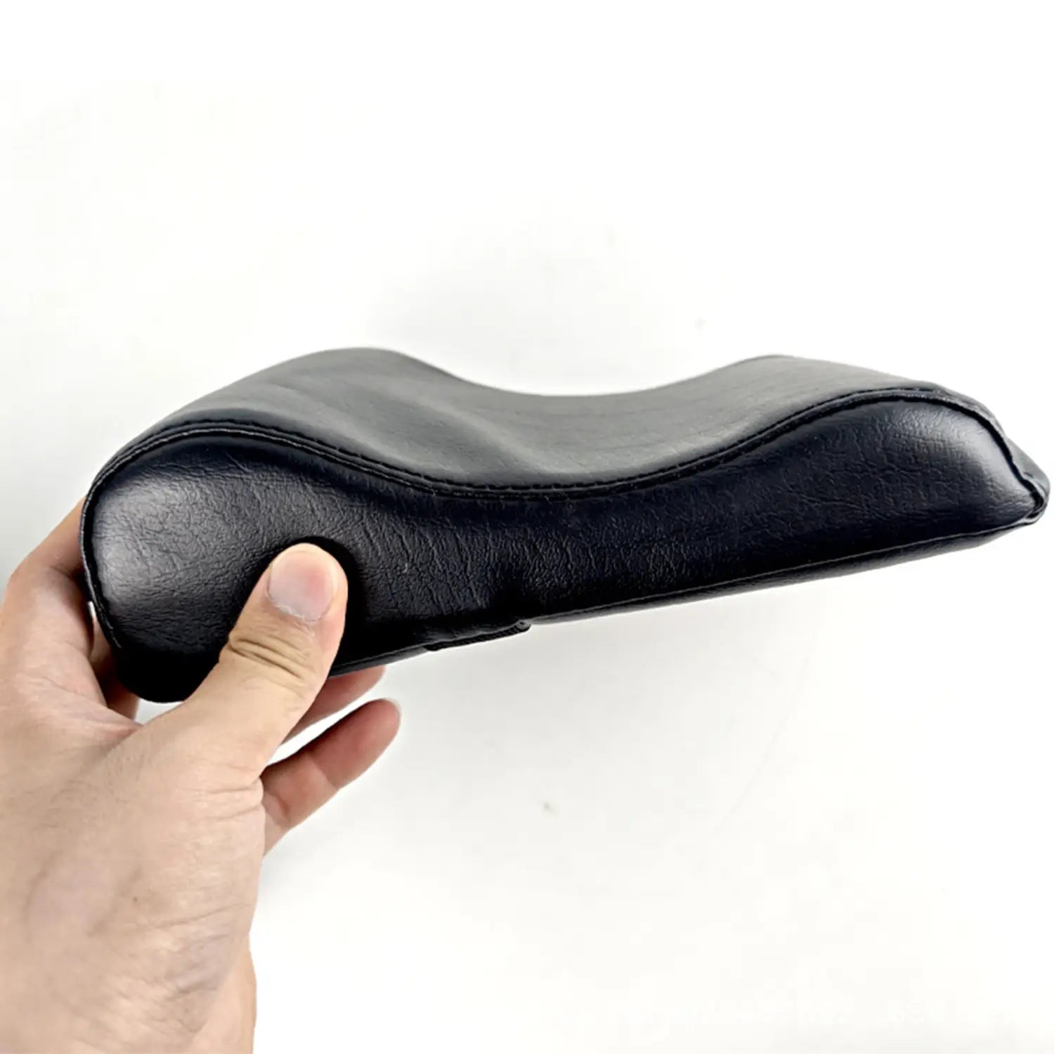 black leather neck support pillow with contoured ergonomic design for pilates reformer use providing effective neck support.
