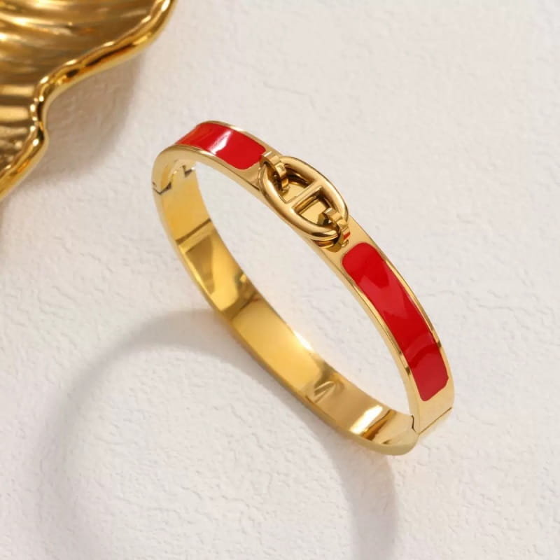 Gold-tone women h bangle featuring vibrant red enamel accents and a classic interlocking logo clasp in a fashion bracelet minimalist design.