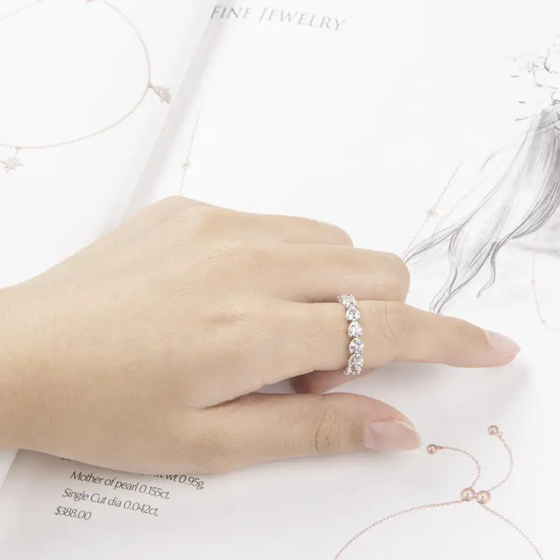 Une bague d’éternité cœur en argent sterling, dotée d’une bande argentée délicate ornée d’une rangée de diamants ronds étincelants.