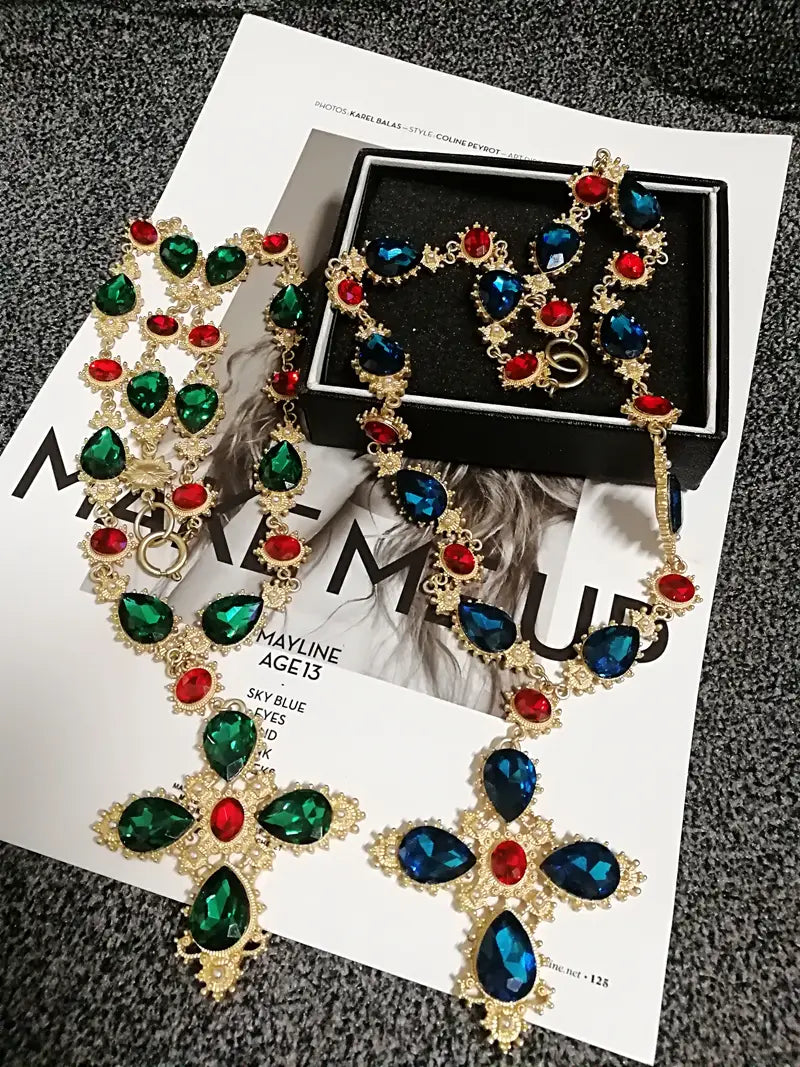 Collier ras du cou à déclaration en cristal à finition dorée, éblouissant, avec un pendentif en forme de croix orné et affirmé, agrémenté de cristaux vifs vert et bleu profond en forme de larme, et de pierres rouges plus petites, pour des bijoux de soirée.
