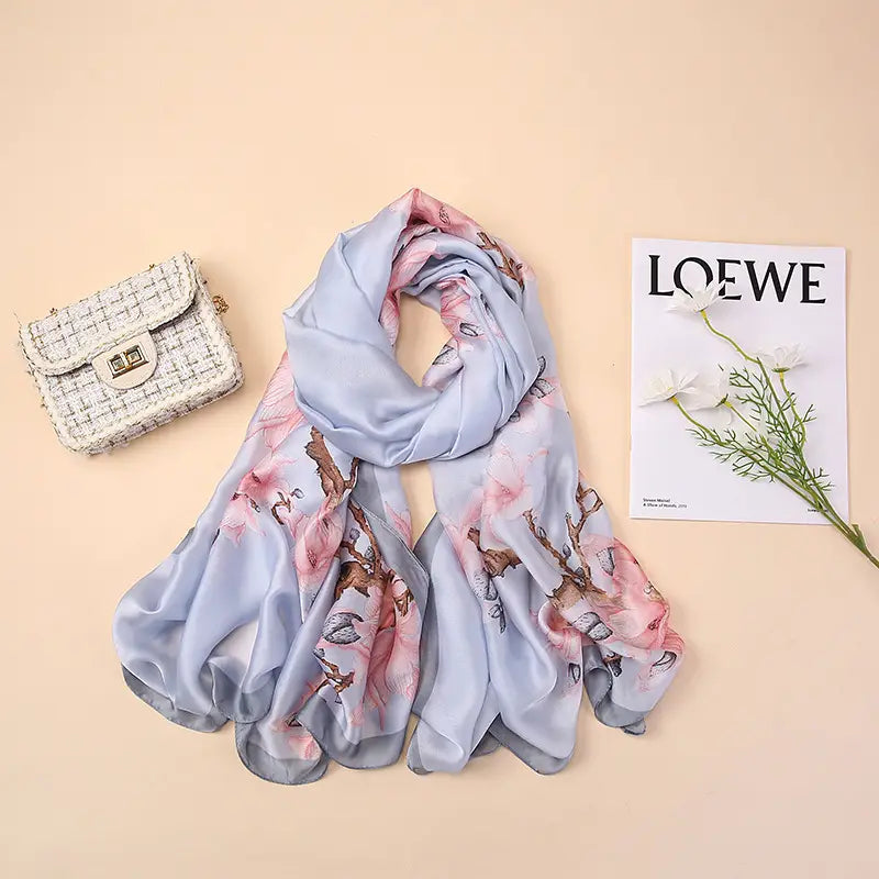 Un châle foulard en soie bleu clair délicat, présentant des motifs floraux rose pâle et des branches brunes, inspirés par les amandiers en fleurs de Van Gogh