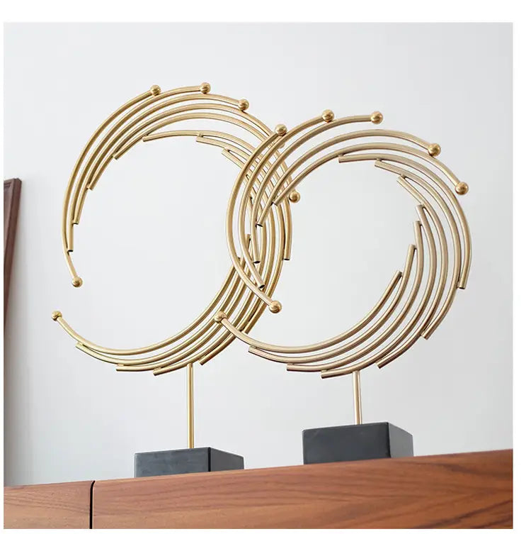 Gold metal abstract sculpture featuring gold-toned metal interlocking circular rings with small spherical accents for office desk decor.