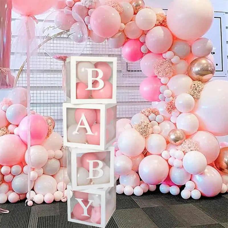 Letras de bloques para bebé de acrílico transparente que deletrean «baby» con letras mayúsculas blancas apiladas verticalmente en un juego de caja con globos transparente para baby shower.