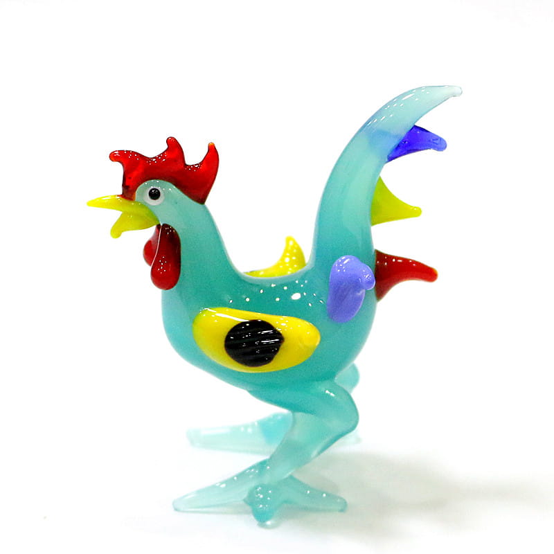A vibrant turquoise glass rooster miniature figurine with a red comb yellow beak and colorful purple blue and yellow patches designed as an Easter ornament.
