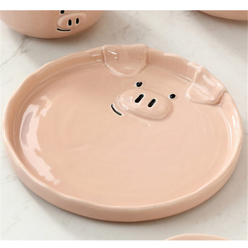 Pastel pink ceramic pig-shaped tray with black dot eyes and snout details from the cute pig ceramic dinnerware set.