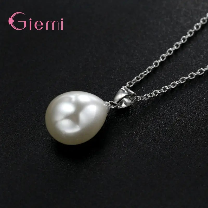 Un brillante dije de perla blanca en forma de lágrima del conjunto de joyas de perlas de plata esterlina, suspendido en una delicada cadena de plata, con un cierre metálico elegante con la marca Giemi.