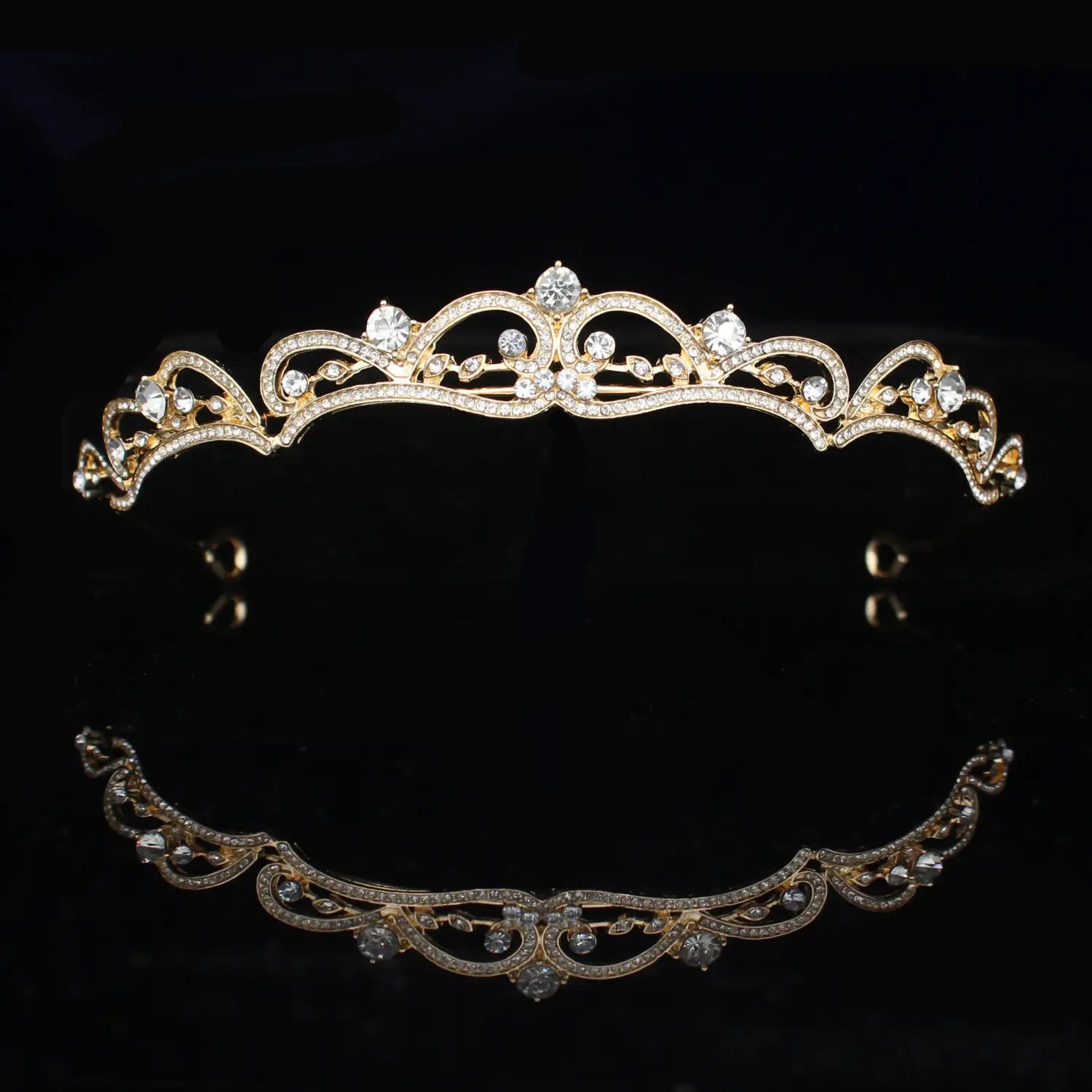 Una tiara de novia de cristal dorado delicada adornada con cristales transparentes brillantes en un diseño floral ornamentado e intrincado para diadema de boda.