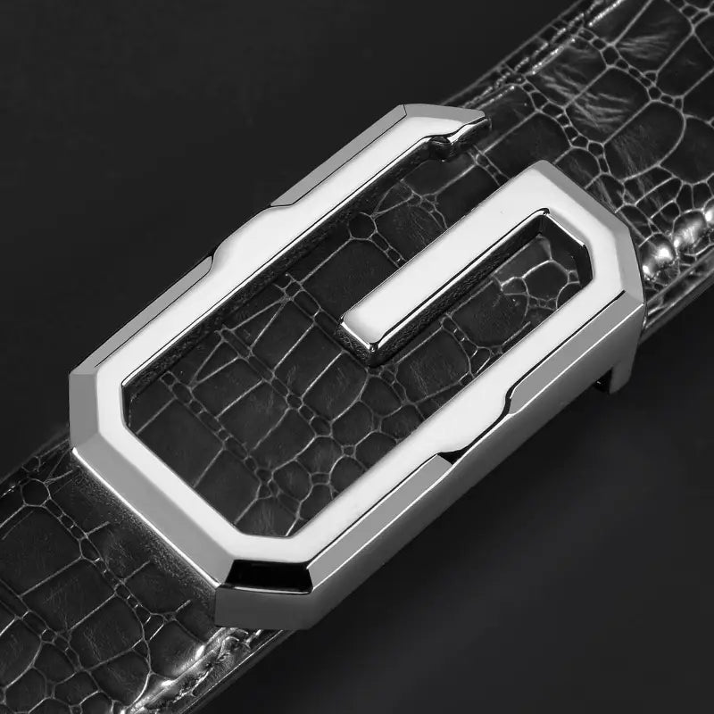 Herren-Gürtel aus Krokodilleder mit silberfarben getöneter, geometrisch geformter Schnalle und einer eleganten metallischen Oberfläche auf einem schwarzen Krokodil-napoleonmustergeprägten Lederriemen.
