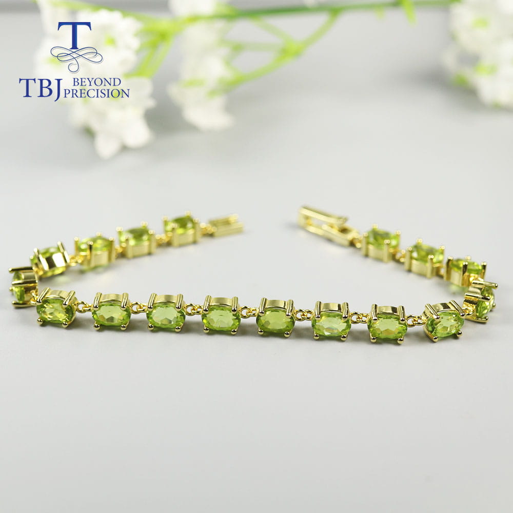 Una pulsera tipo tenis delicada de plata de ley con peridoto en tono dorado, con una fila de vibrantes piedras de peridoto verde, colocadas en elegantes biseles.