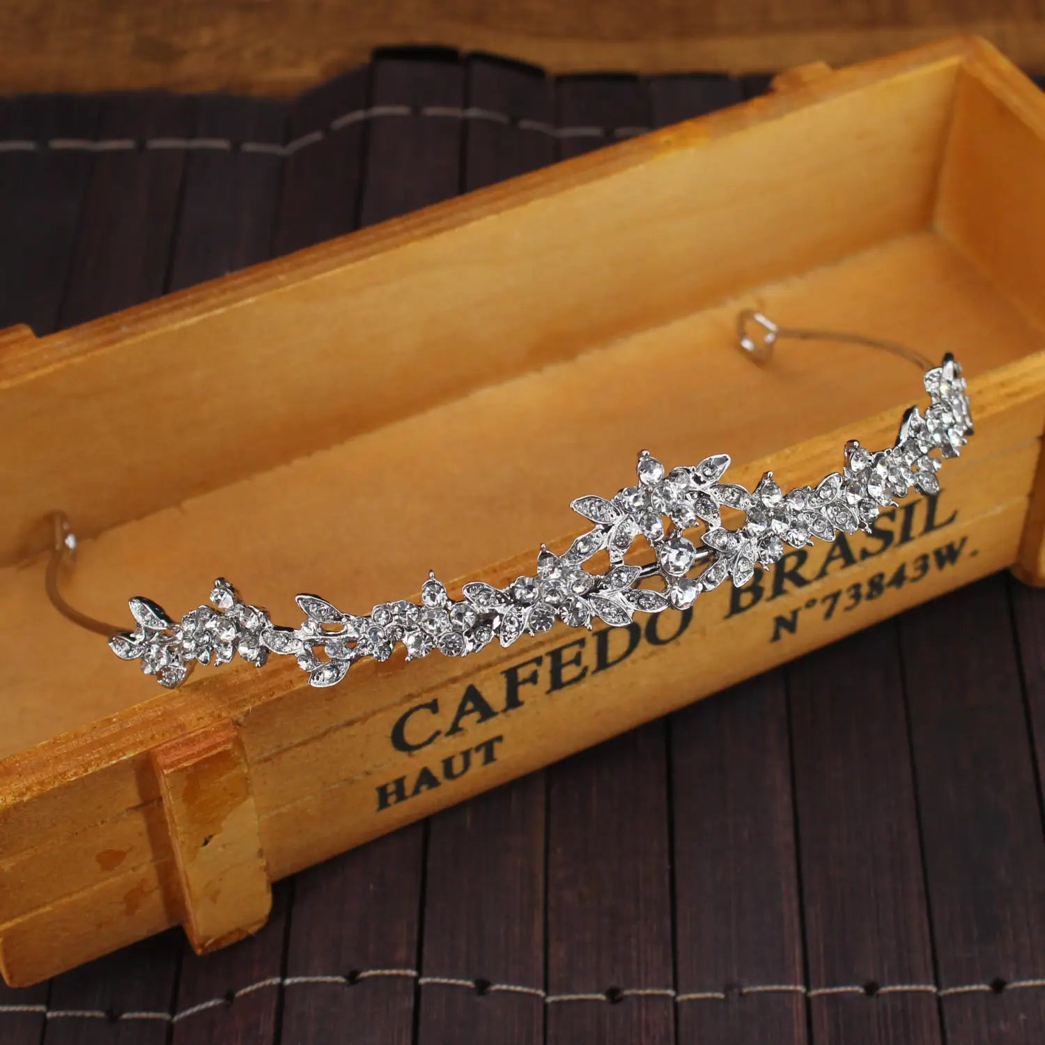 Diadema floral para boda plateada adornada con pedrería brillante en un diseño de tiara de novia de cristal.