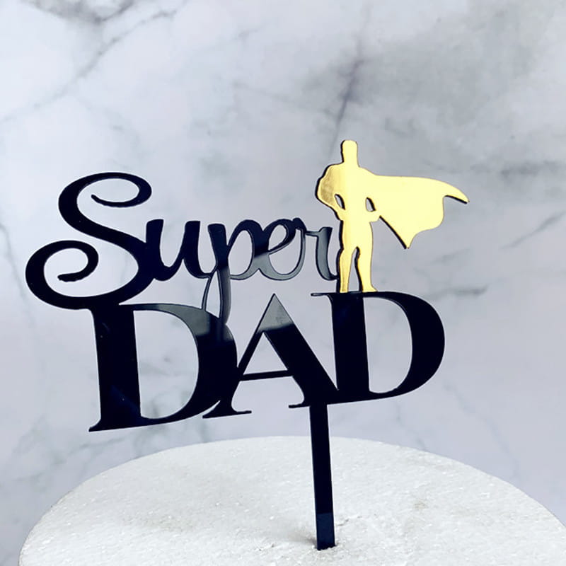 Gold acrylic superhero silhouette cake topper featuring super dad in black cursive and block lettering for Father’s Day celebration.