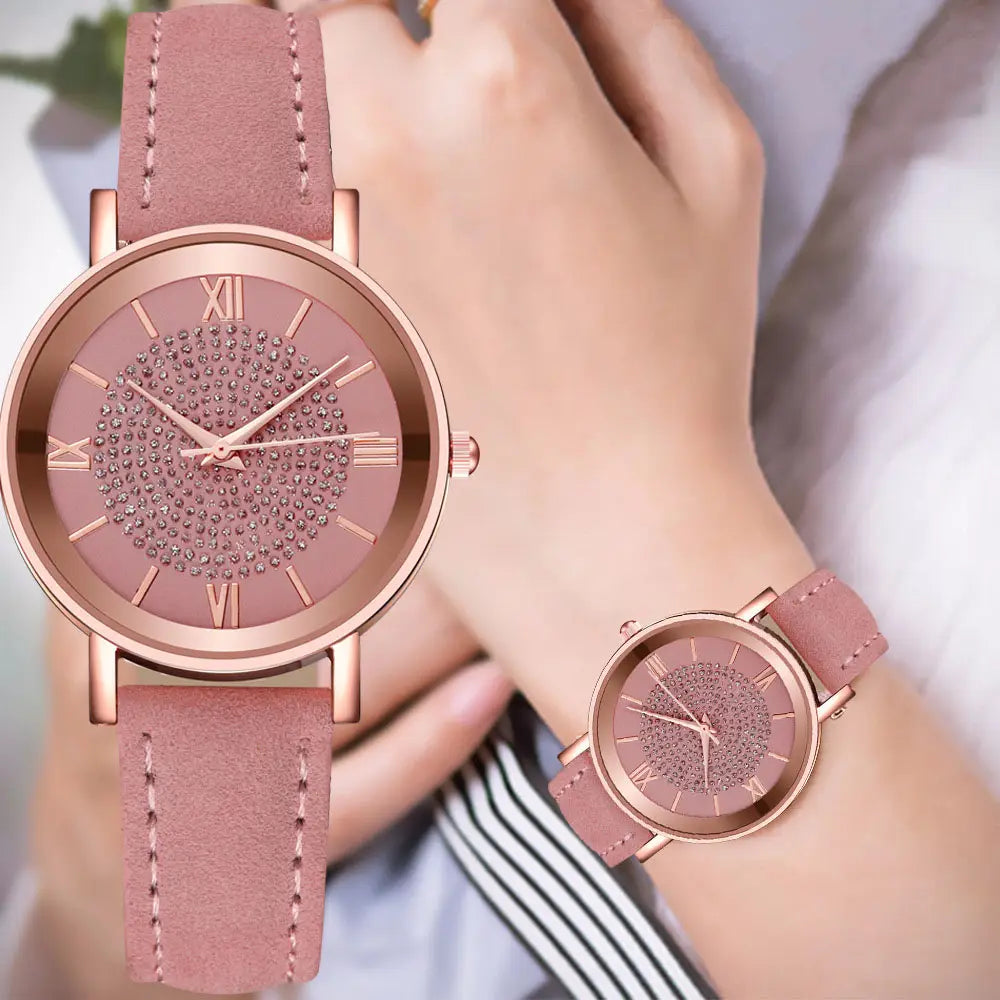 Rose gold crystal quartz women watch with a pink suede leather strap and a face adorned with sparkling rhinestones and roman numerals.