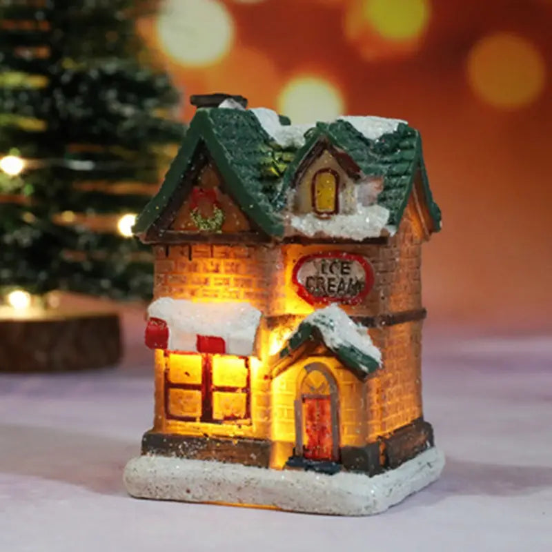 Une figurine miniature de boutique de glace du village de Noël à LED, illuminée, avec un toit vert, des murs aspect brique et des détails blanchis par la neige, veilleuse à batterie.
