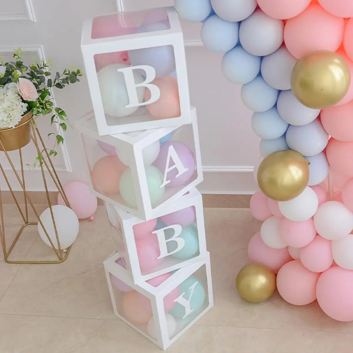 Bloques transparentes blancos apilados para bebé con globos de colores pastel en su interior y las letras «baby» impresas en cada cara, en un juego de caja con globos transparente para baby shower.
