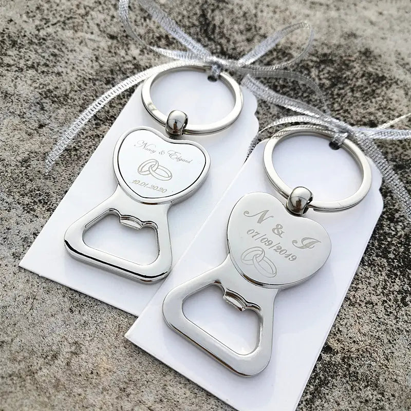 Décapsuleurs en forme de cœur argentés gravés des initiales et de la date du mariage, fixés à des anneaux de clé personnalisés comme faveurs de mariage.