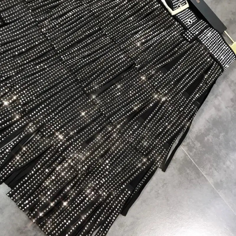 Mini-jupe noire à franges taille haute, agrémentée de strass scintillants et d’une ceinture assortie à rivets.