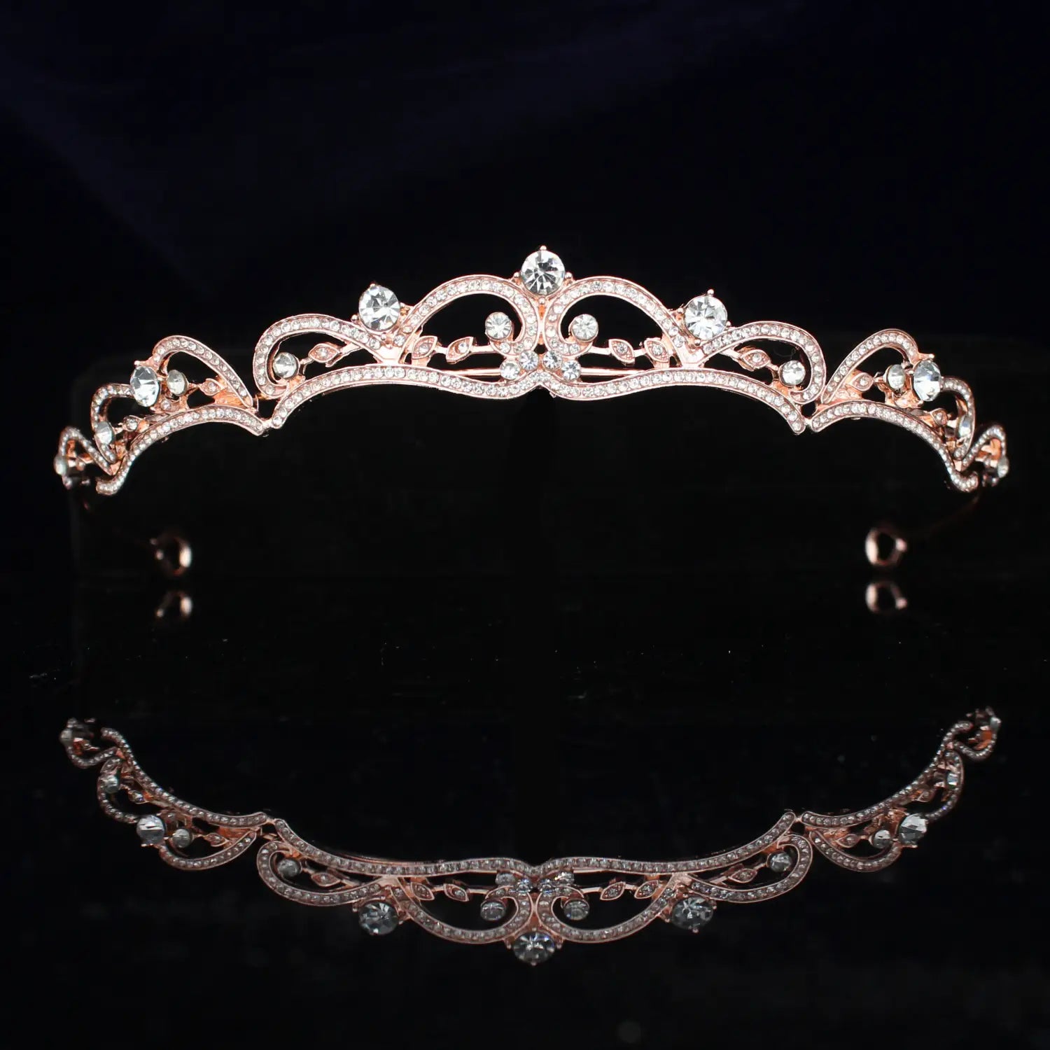 Una tiara de novia de cristal rosa dorado delicada con cristales transparentes brillantes y un detallado intrincado tipo filigrana de hojas para bodas.