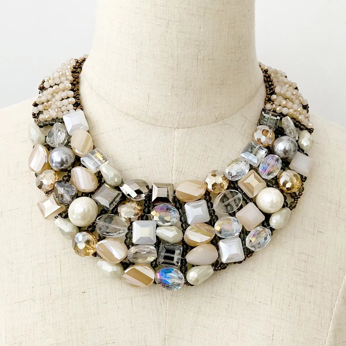 A crystal pearl statement choker necklace featuring a multi-layered design with clear silver and cream-colored crystals and pearls set in a dark metal framework.