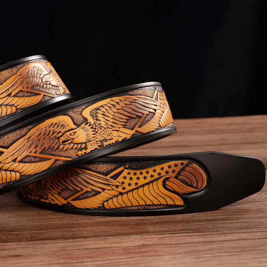 Ceinture à cliquet en cuir pour homme de couleur camel, avec des motifs d’aigle finement sculptés, des ailes déployées et une queue constellée encadrée par des bords noirs.