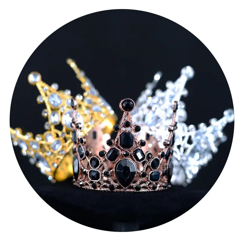 Ein Mini-Kronen-Tortenaufsatz und eine Haar-Tiara aus Roségold, verziert mit schwarzen und klaren facettierten Edelsteinen.