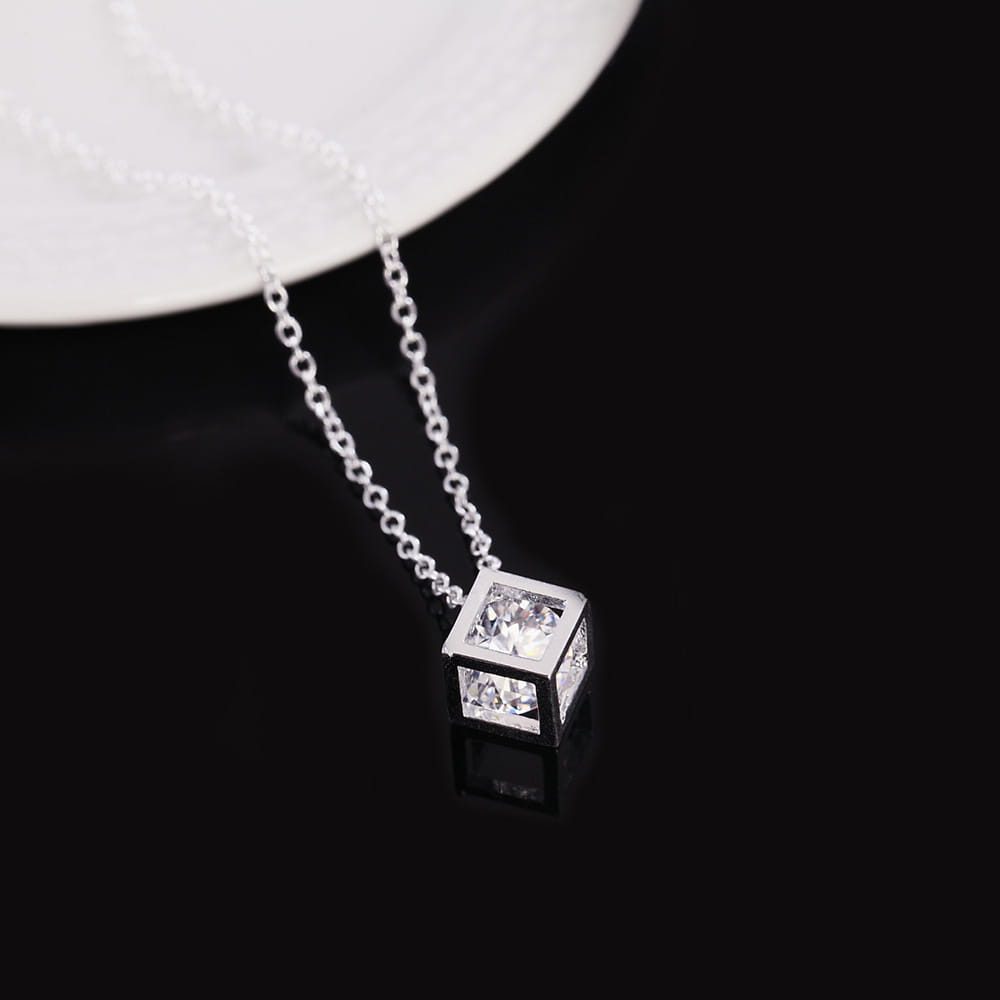 Collier de pendentif en zirconium carré argenté élégant, présentant une pierre précieuse transparente à facettes disposée sur chacune de ses quatre faces visibles, suspendue à une chaîne raffinée.