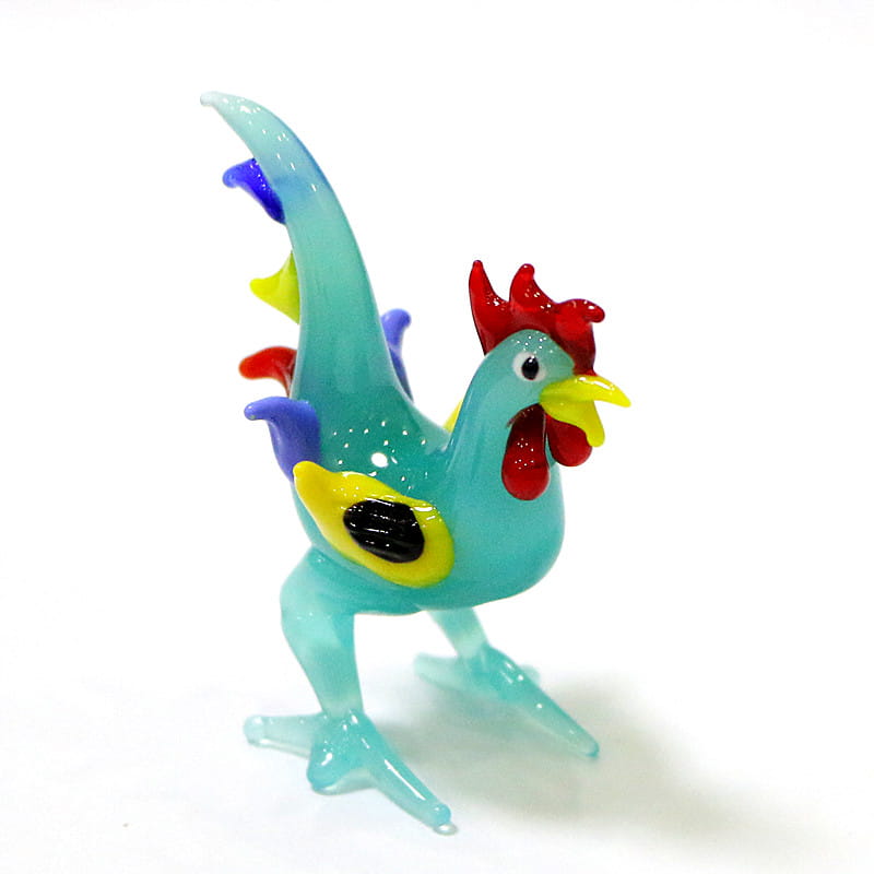A vibrant turquoise glass rooster miniature figurine with a red comb, yellow beak and wattle, and multicolored feather accents in blue, purple, and green, designed as an Easter ornament.