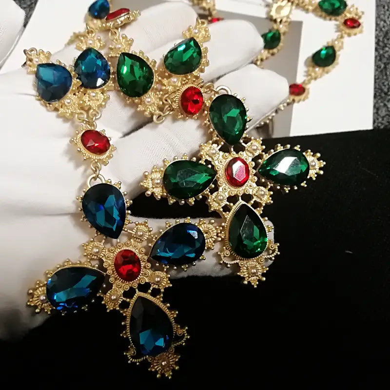 Collier ras du cou à déclaration en cristal à finition dorée, somptueux, mettant en valeur de grands cristaux facettés bleu profond et vert émeraude en forme de larme, rehaussés de pierres rouges plus petites, pour des bijoux de soirée.