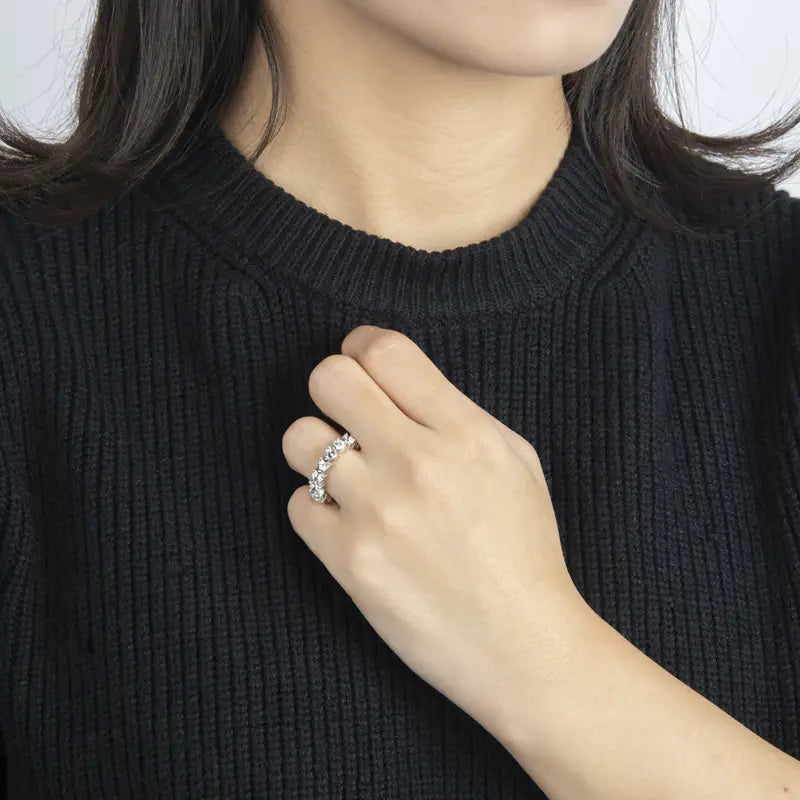 Une bague d’éternité cœur en argent sterling, dotée d’une bande argentée étincelante ornée d’une rangée de pierres facettées transparentes, disposées dans une courbe élégante.