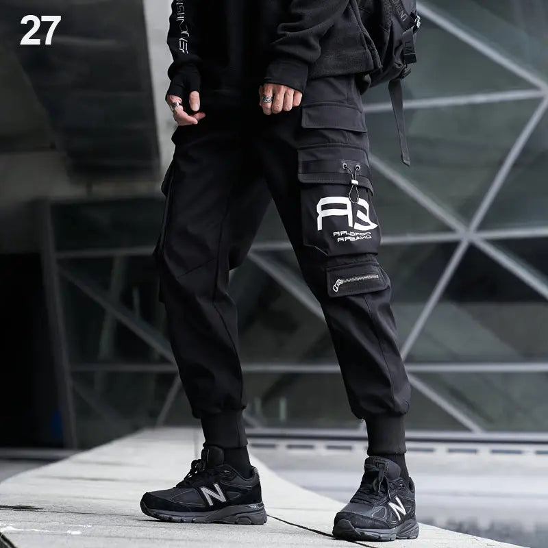 Herren schwarze taktische Cargo-Jogginghosen mit mehreren Taschen und einem weißen Logo am Oberschenkel im Streetwear-Stil.