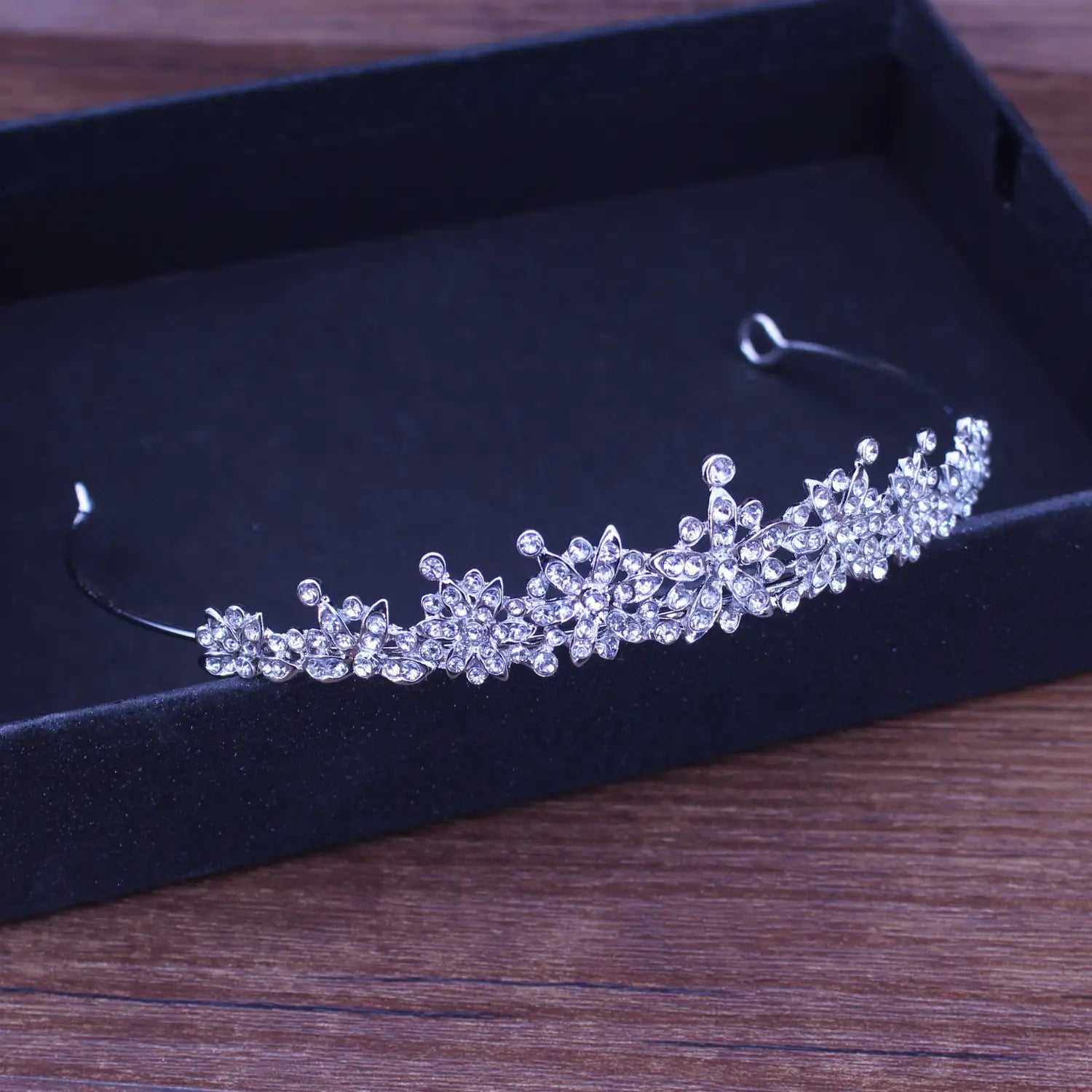 Una diadema de boda floral con tiara de novia delicada de cristal plateado, adornada con cristales transparentes brillantes dispuestos en un intrincado patrón floral.