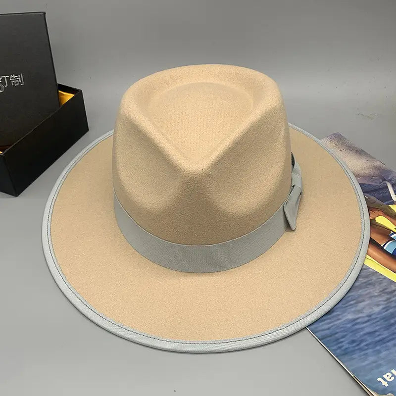 Beige woolen felt fedora hat with feather accent featuring a light gray ribbon band and matching stitched trim.