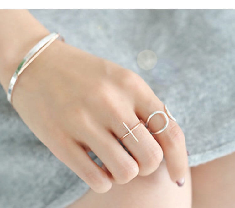 A minimalist gold-toned sterling silver adjustable open ring for women featuring a simple cross design worn on the middle finger.