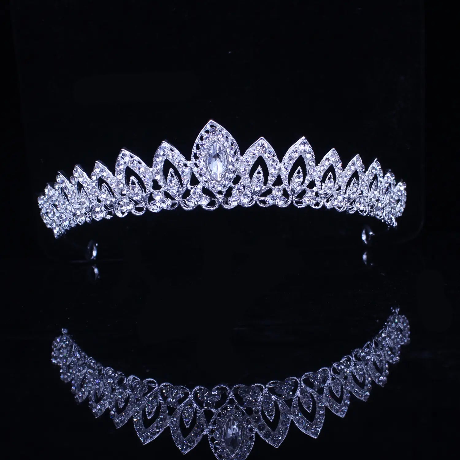 Una tiara de novia de cristal plateado brillante con patrones intrincados con forma de hojas y un cristal central en talla marquesa rodeado de pedrería transparente para su uso como diadema de boda.
