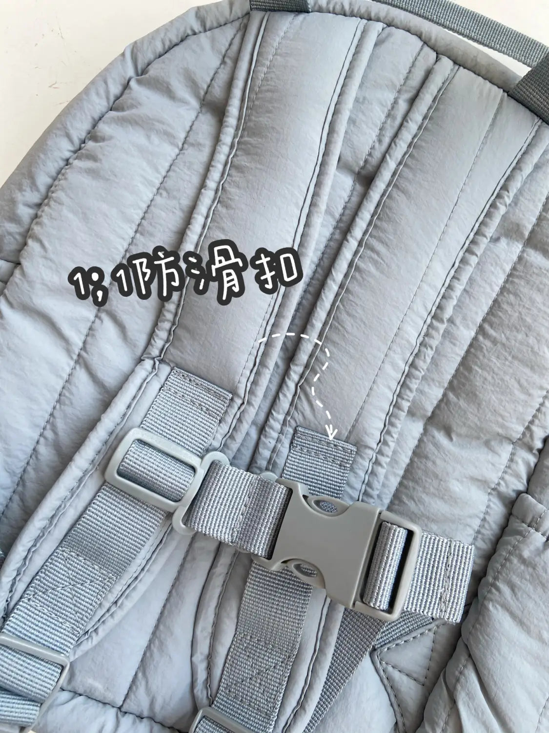 Grau gesteppter Rucksack-Gurt mit grauer Kunststoffschnalle und gewebtem Stoff auf der Rückseite eines wasserfesten Kinder-gesteppten, bestickten Schulrucksacks